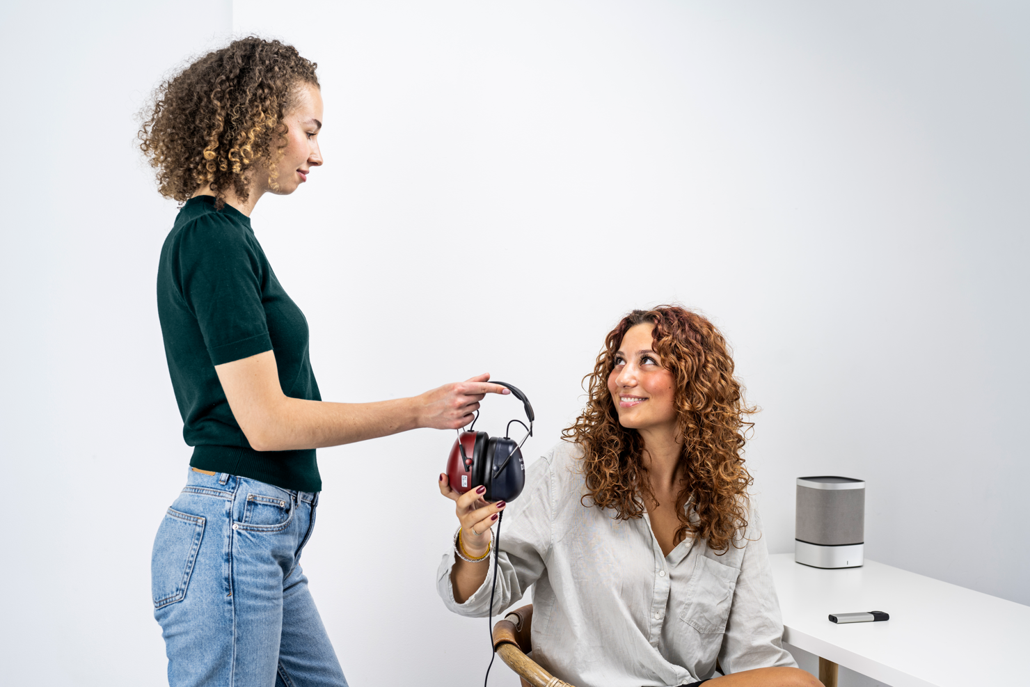 Audiologist handing headphones to patient before a pure-tone hearing test, one of the most common types of hearing tests